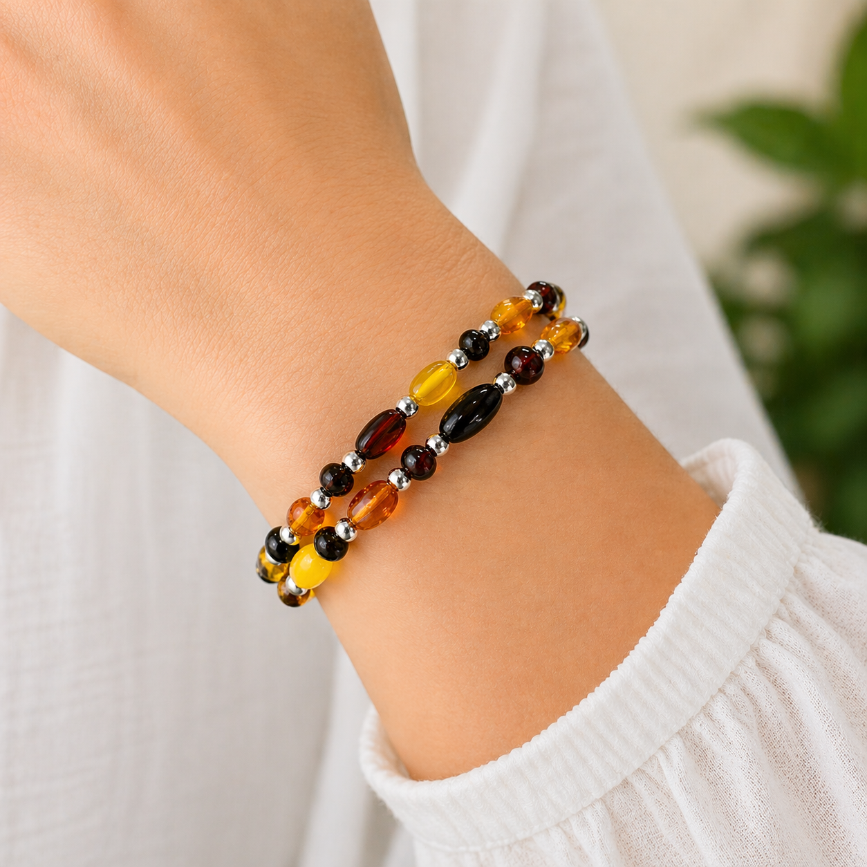Doppelreihiges Bernstein Armband in Gelb, Cognac und Schwarz am Handgelenk getragen mit silbernen Zwischenelementen