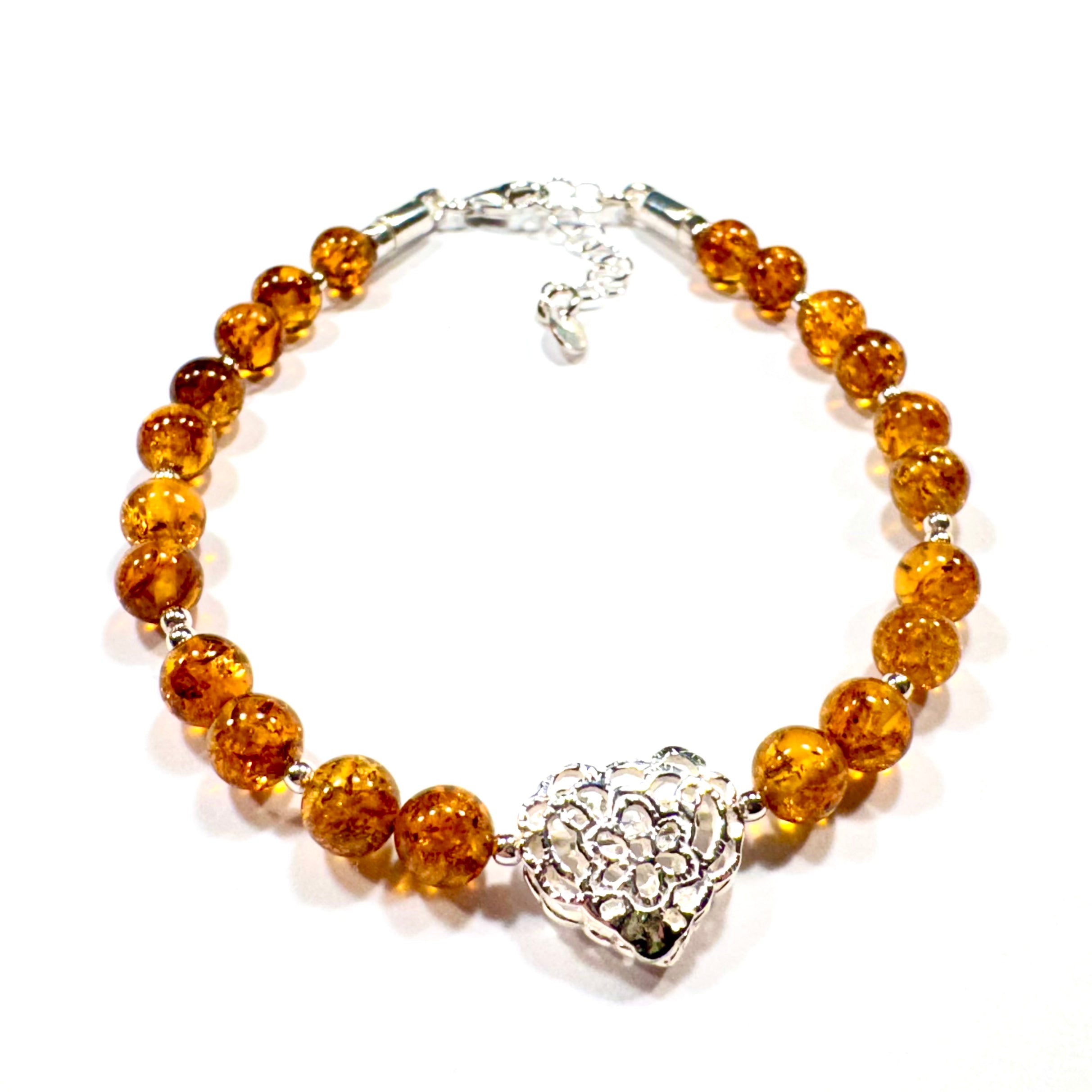 Handgefertigtes Bernstein-Armband mit Naturbernstein-Perlen in warmen Farbtönen und zartem Herz-Charm – eleganter Schmuck mit romantischer Note.