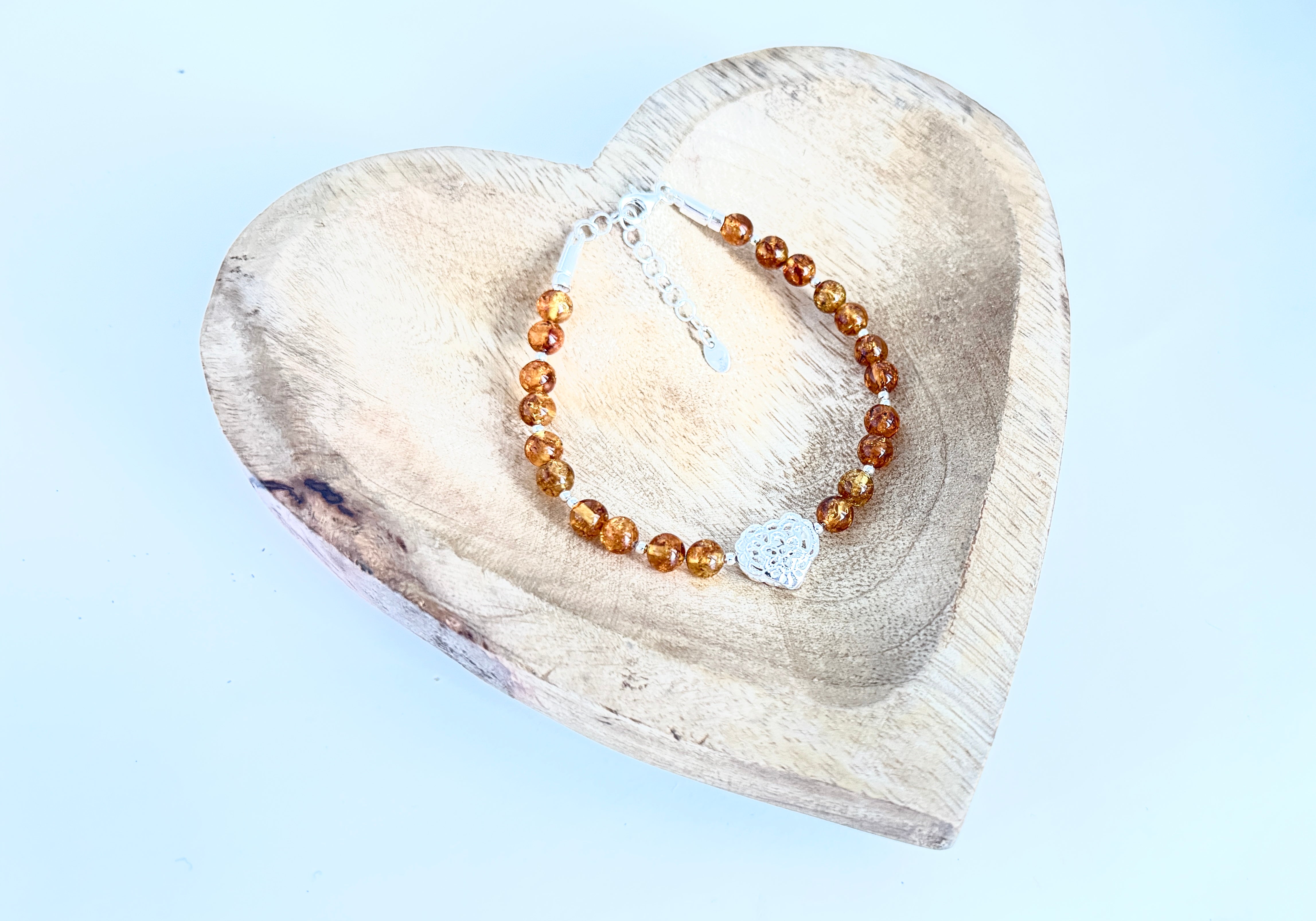 Handgefertigtes Bernstein-Armband mit Naturbernstein-Perlen in warmen Farbtönen und zartem Herz-Charm – eleganter Schmuck mit romantischer Note.