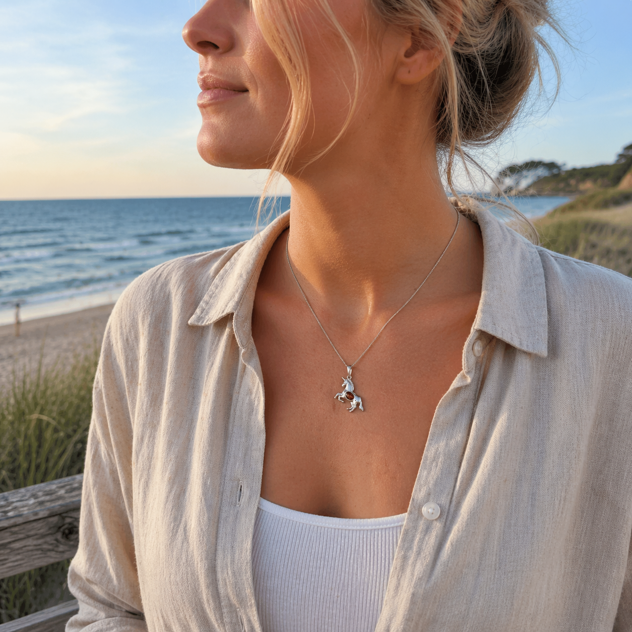 Frau trägt Bernstein Halskette mit Einhorn Anhänger aus Silber – maritimer Damenschmuck an der Ostsee