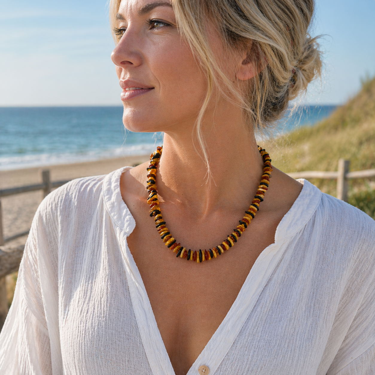 Dame trägt bunte Bernstein Kette am Strand an der Ostsee, maritimer Schmuck aus echtem Bernstein in warmen Naturfarben