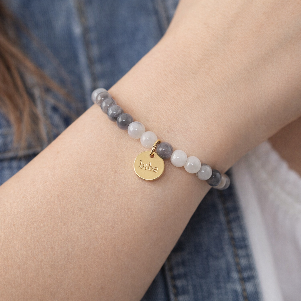 Tragebild Biba Armband mit 6 mm Crystal Perlen in Grau und Weiß mit goldfarbenem Biba Anhänger am Handgelenk