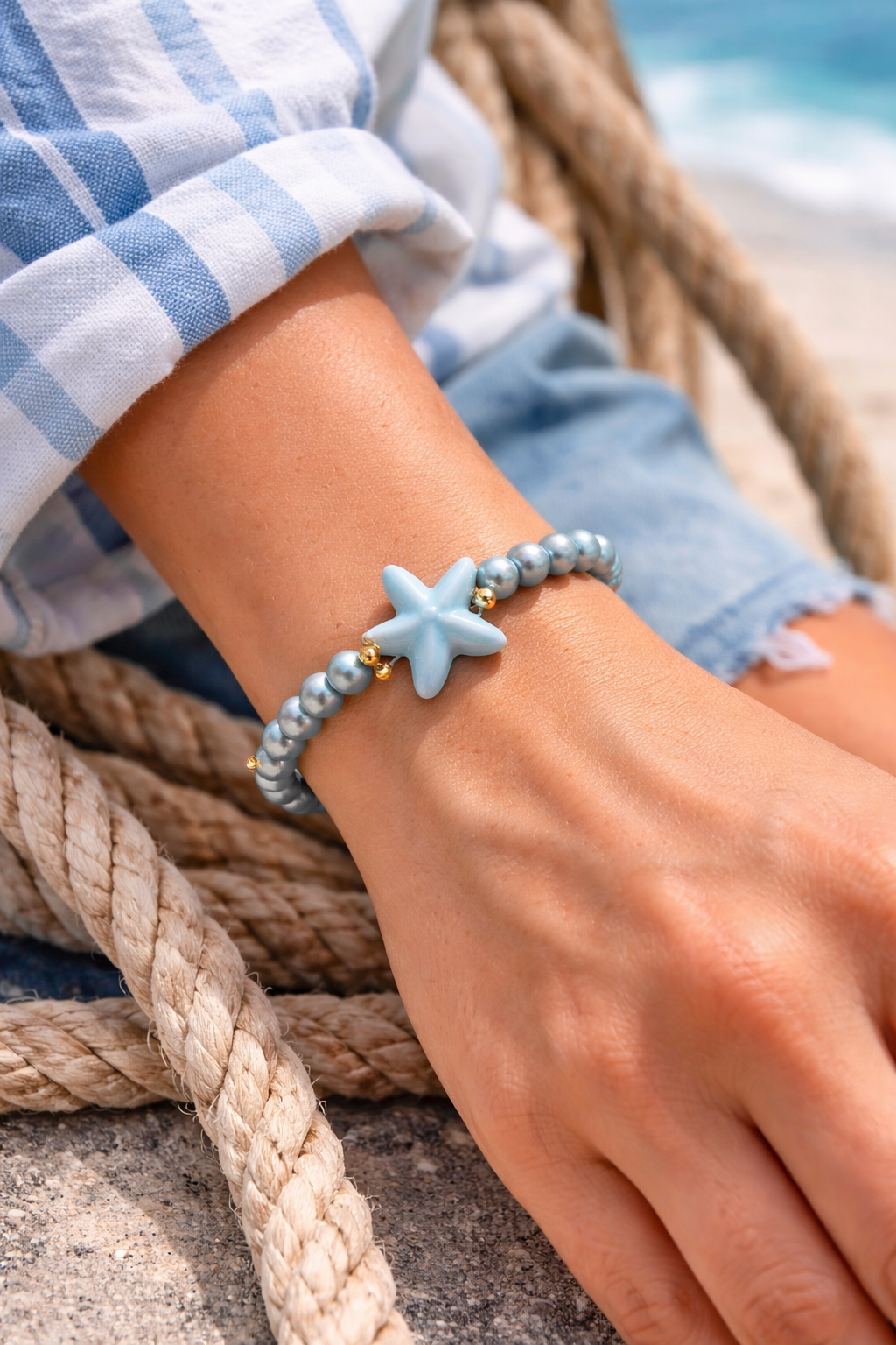 Maritimes Tragebild eines türkisen biba Perlenarmbands mit Seestern und Goldanhänger am Handgelenk