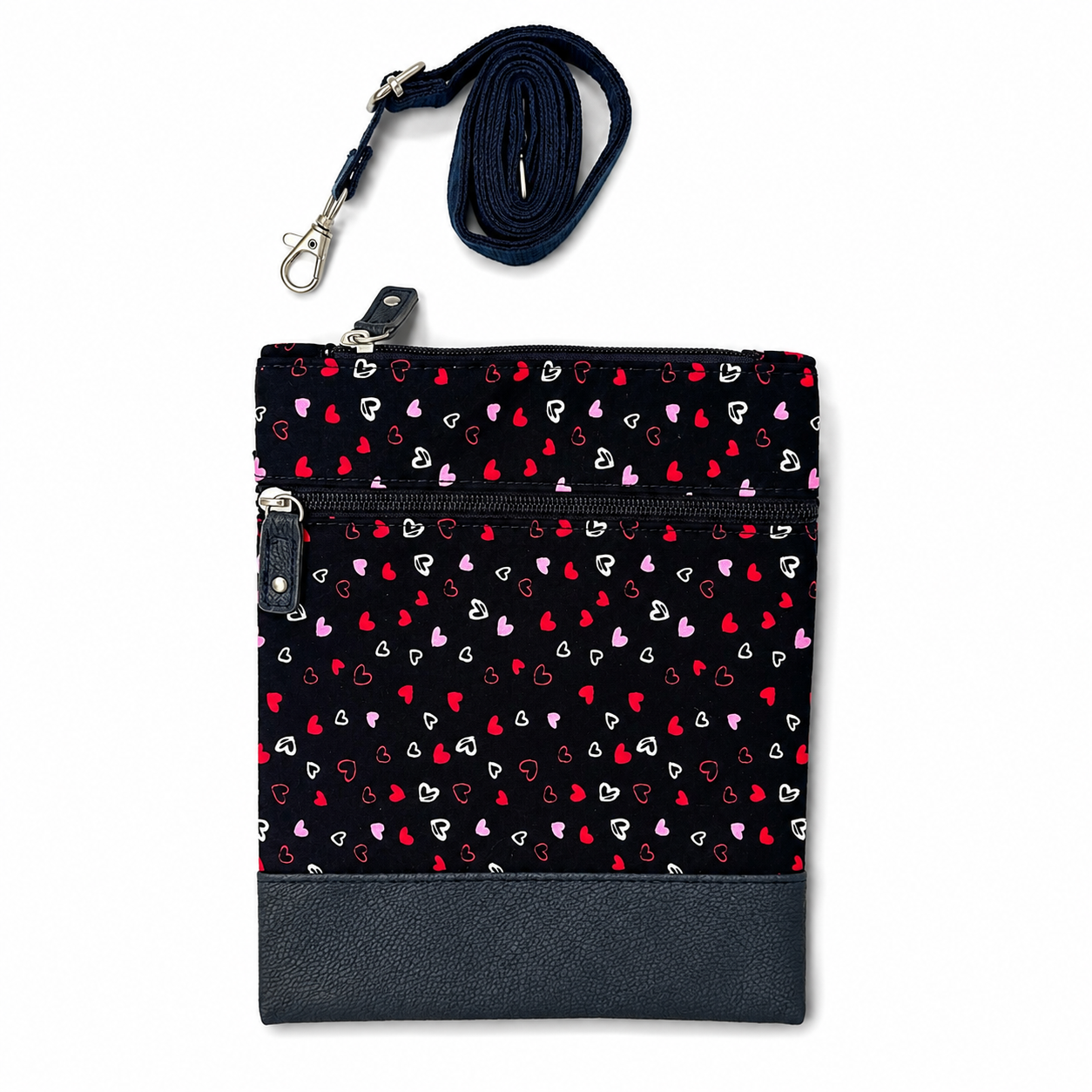 Kleine schwarze Crossbody-Tasche mit Herzmuster, zwei Reißverschlussfächern und Kunstleder-Boden.