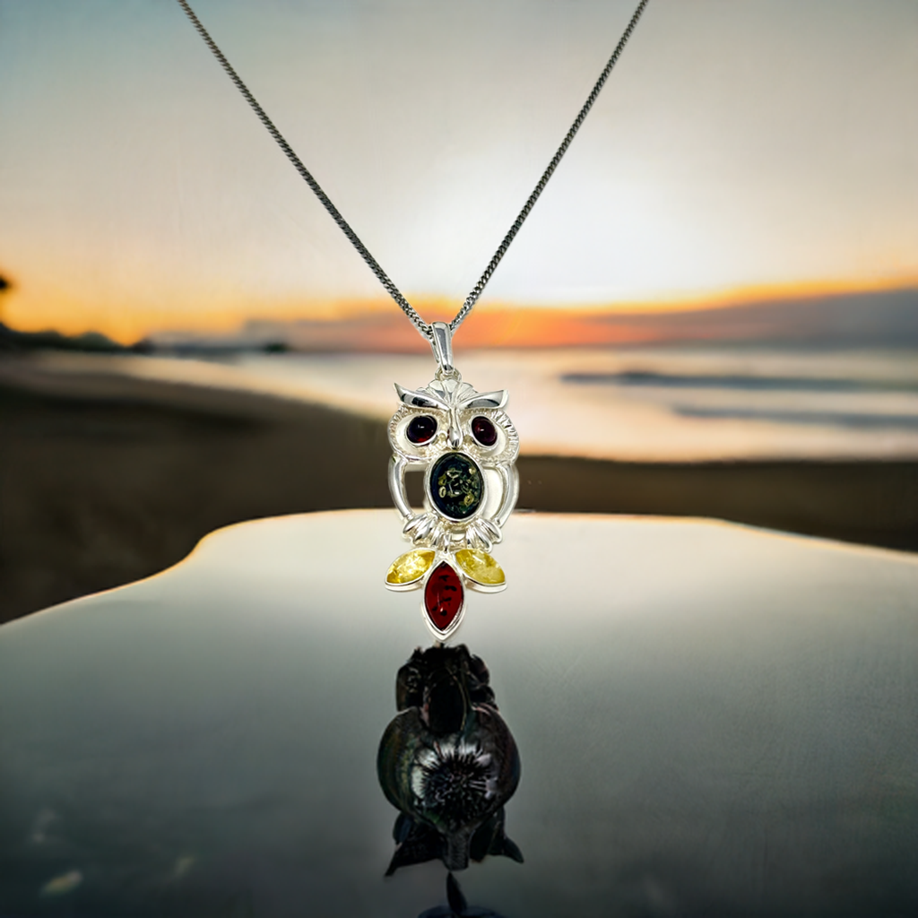 Silberne Halskette mit Eulen-Anhänger, verziert mit mehrfarbigem Bernstein in Braun, Gelb und Grün.