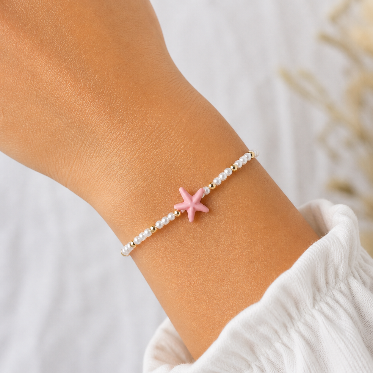 Küstenkind Armband mit rosa Seestern am Handgelenk, zartes Sommerarmband