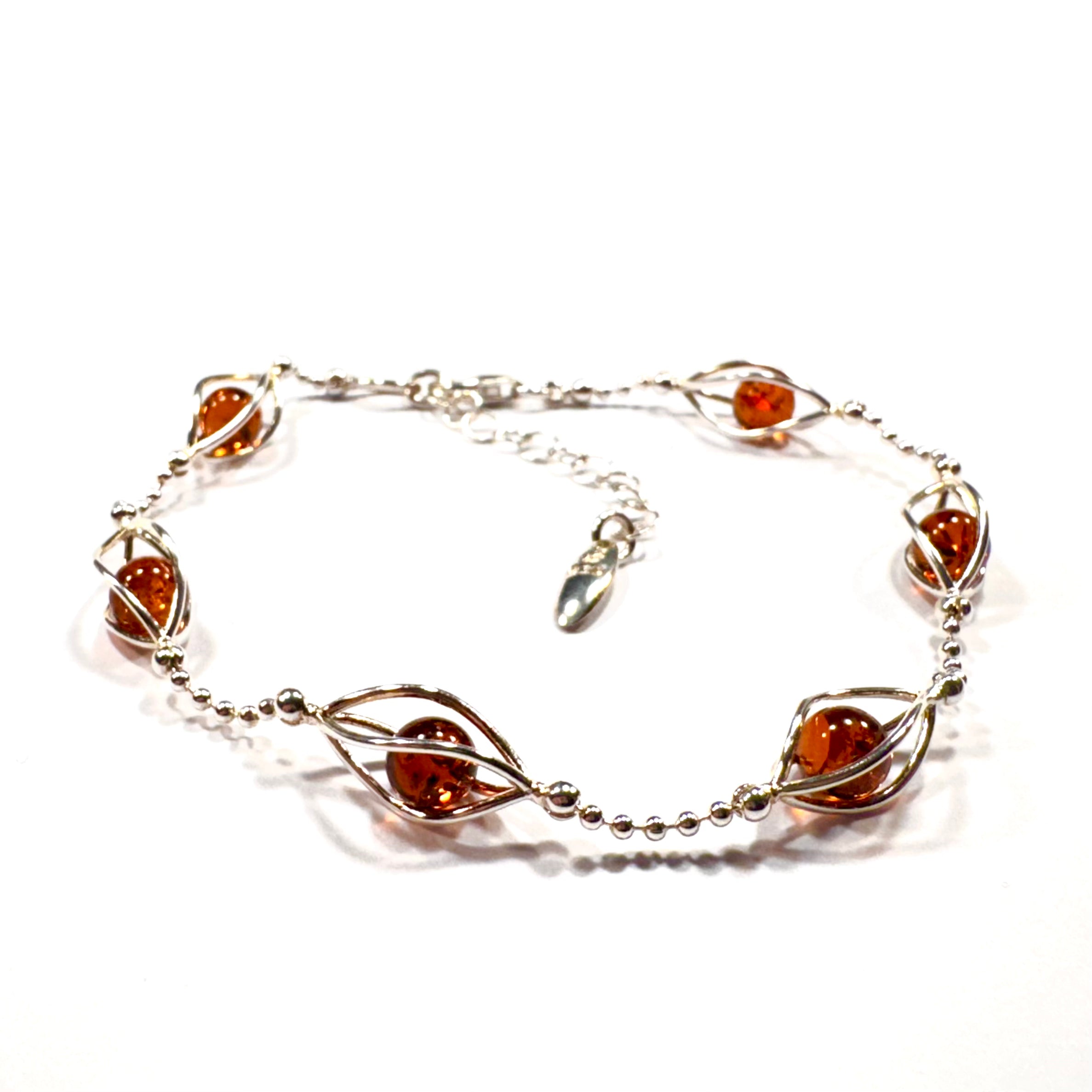 Handgefertigtes Silberarmband mit sechs warmen Bernstein-Perlen, kunstvoll eingefasst in geschwungene Silberdrähte. Verstellbare Länge für perfekten Tragekomfort.