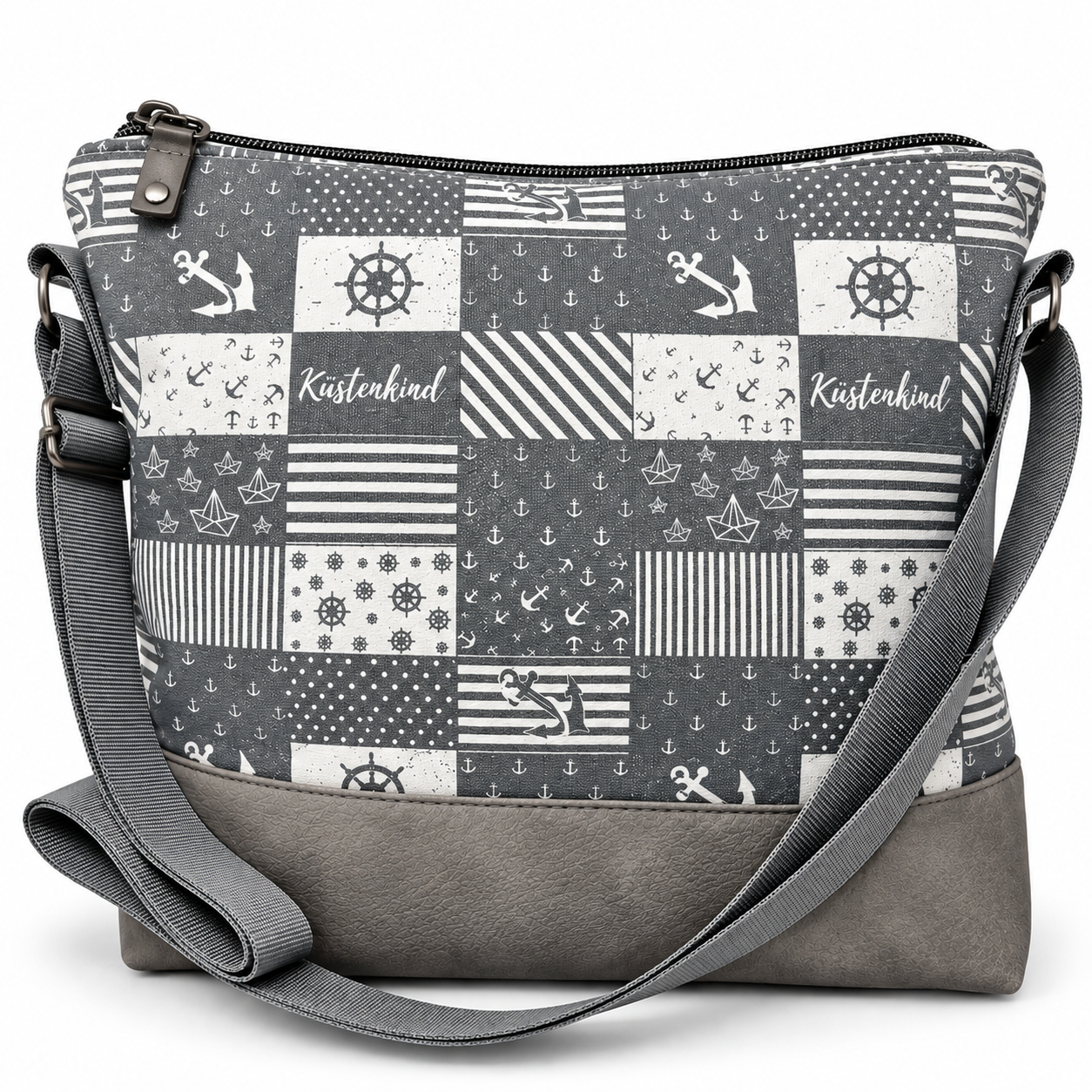 Grau-weiße maritime Umhängetasche Küstenkind mit Patchworkmuster aus Ankern, Steuerrädern, Papierbooten und Streifen sowie grauem Taschenboden und verstellbarem Schultergurt.